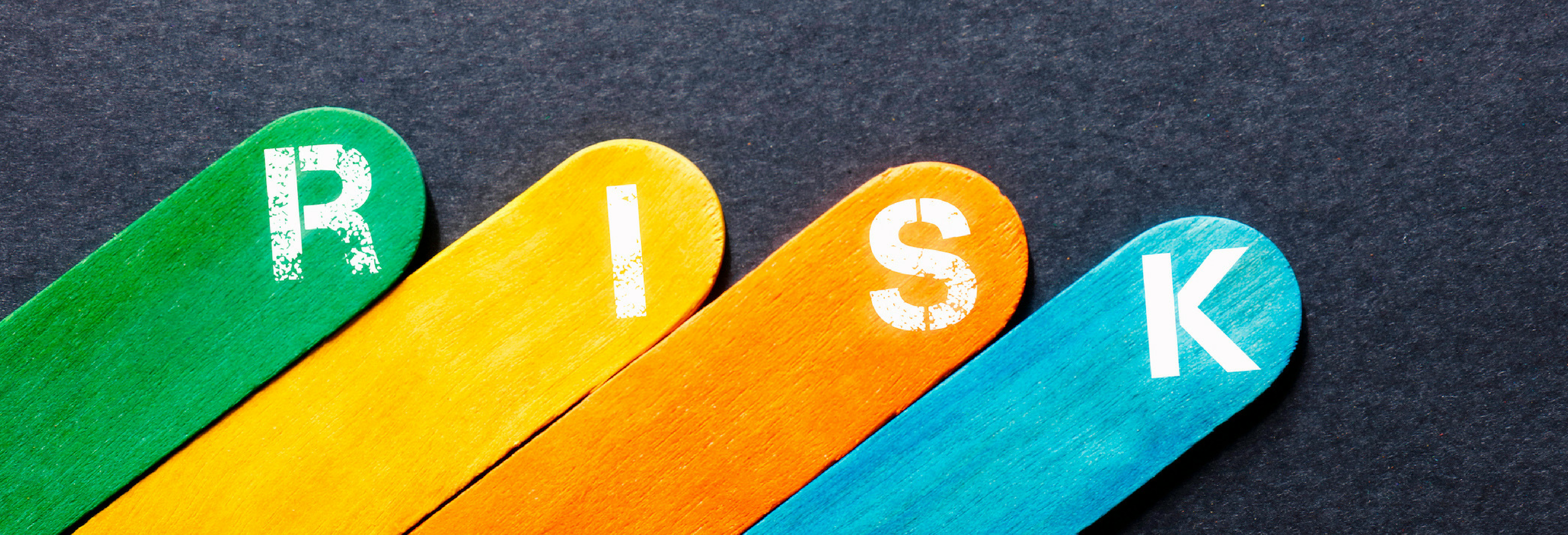 Risk spelled out on individual colored sticks on a black background. 